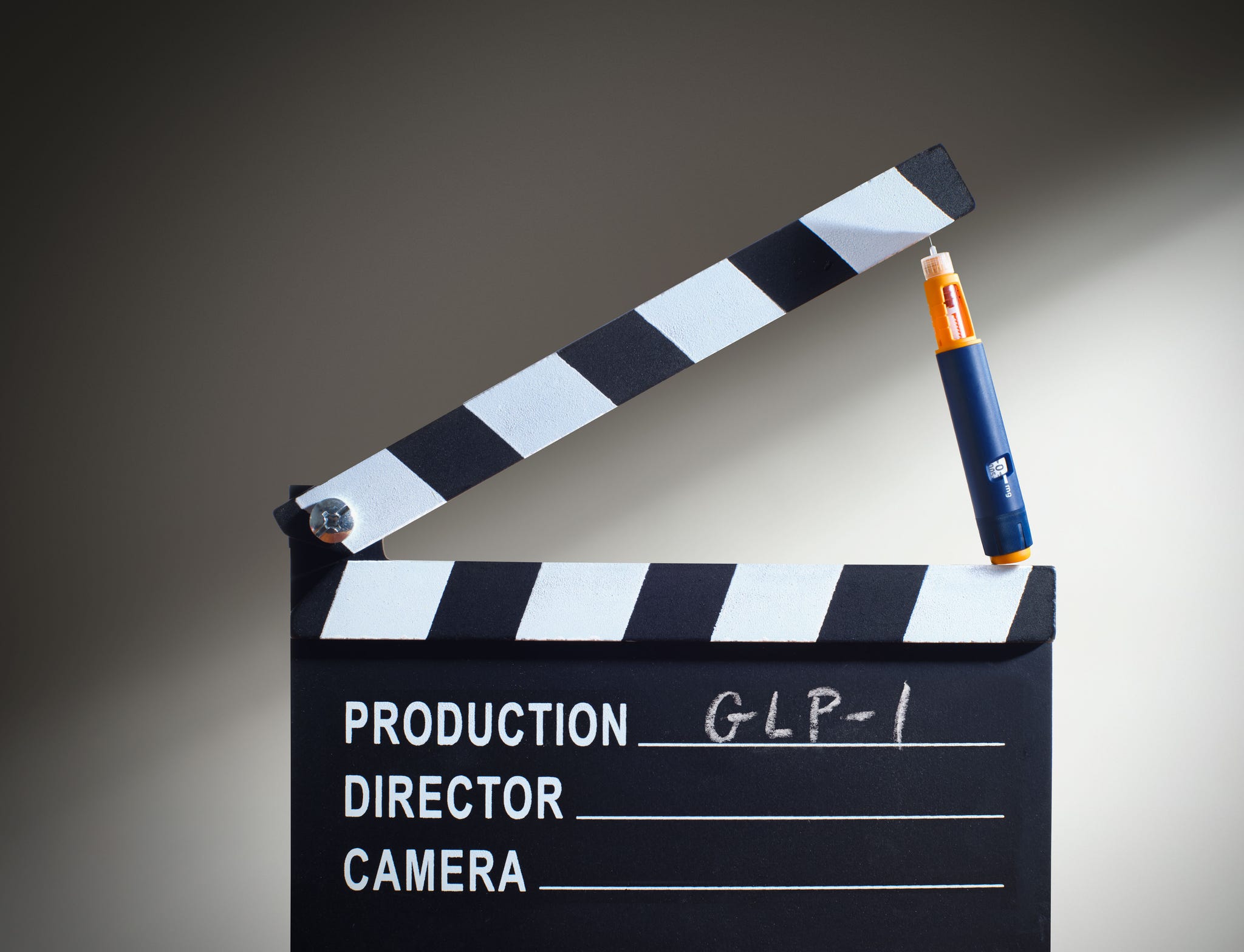 A clapperboard with a pen poised on top, featuring labels for production details and scene information. A clapperboard with a pen poised on top, featuring labels for production details and scene information.