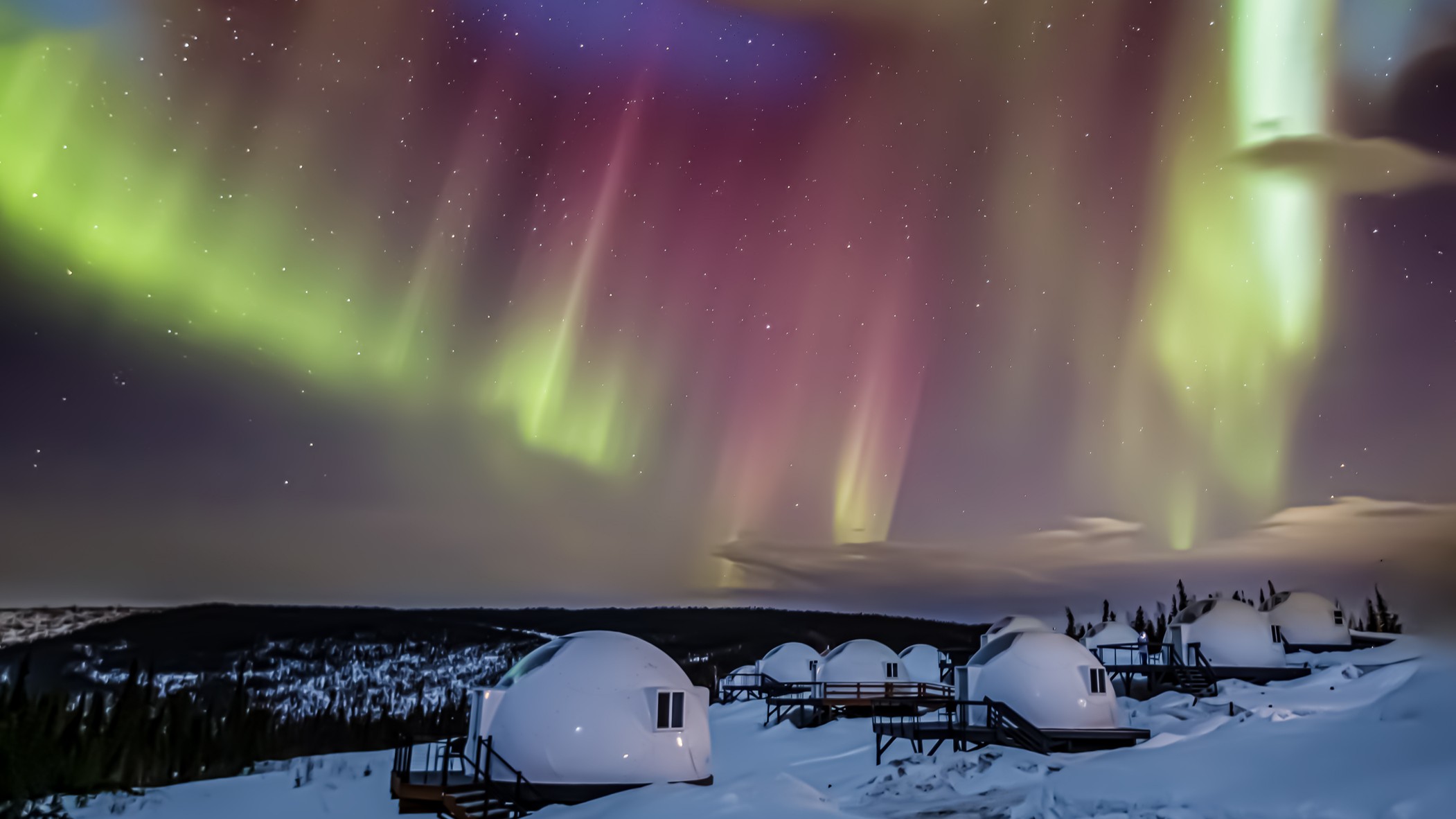 auroras dance in the sky above white spherical "hubs" in a snowy landscape.