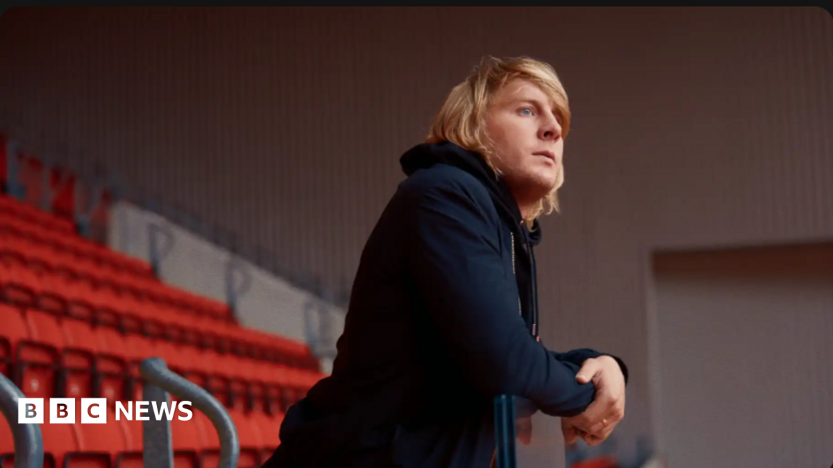 Paddy Pimblett, wearing black, looks out from the stands at Liverpool's Anfield picth