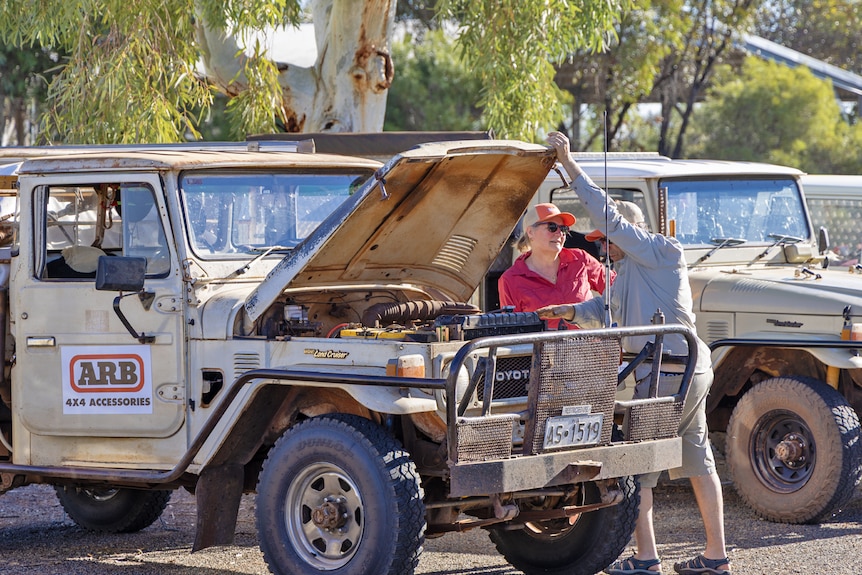 A medium shot of two people looking to a car