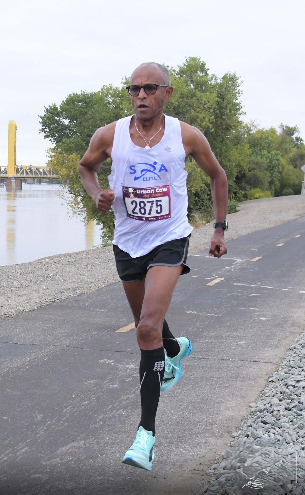 Runner in athletic gear competing in a half marathon along a scenic path by the water.