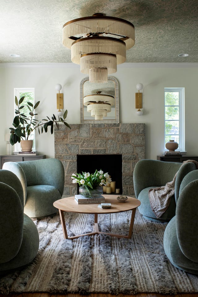 Cozy living room featuring green armchairs, a wooden coffee table, a floral arrangement, and a decorative ceiling light. Cozy living room featuring green armchairs, a wooden coffee table, a floral arrangement, and a decorative ceiling light.