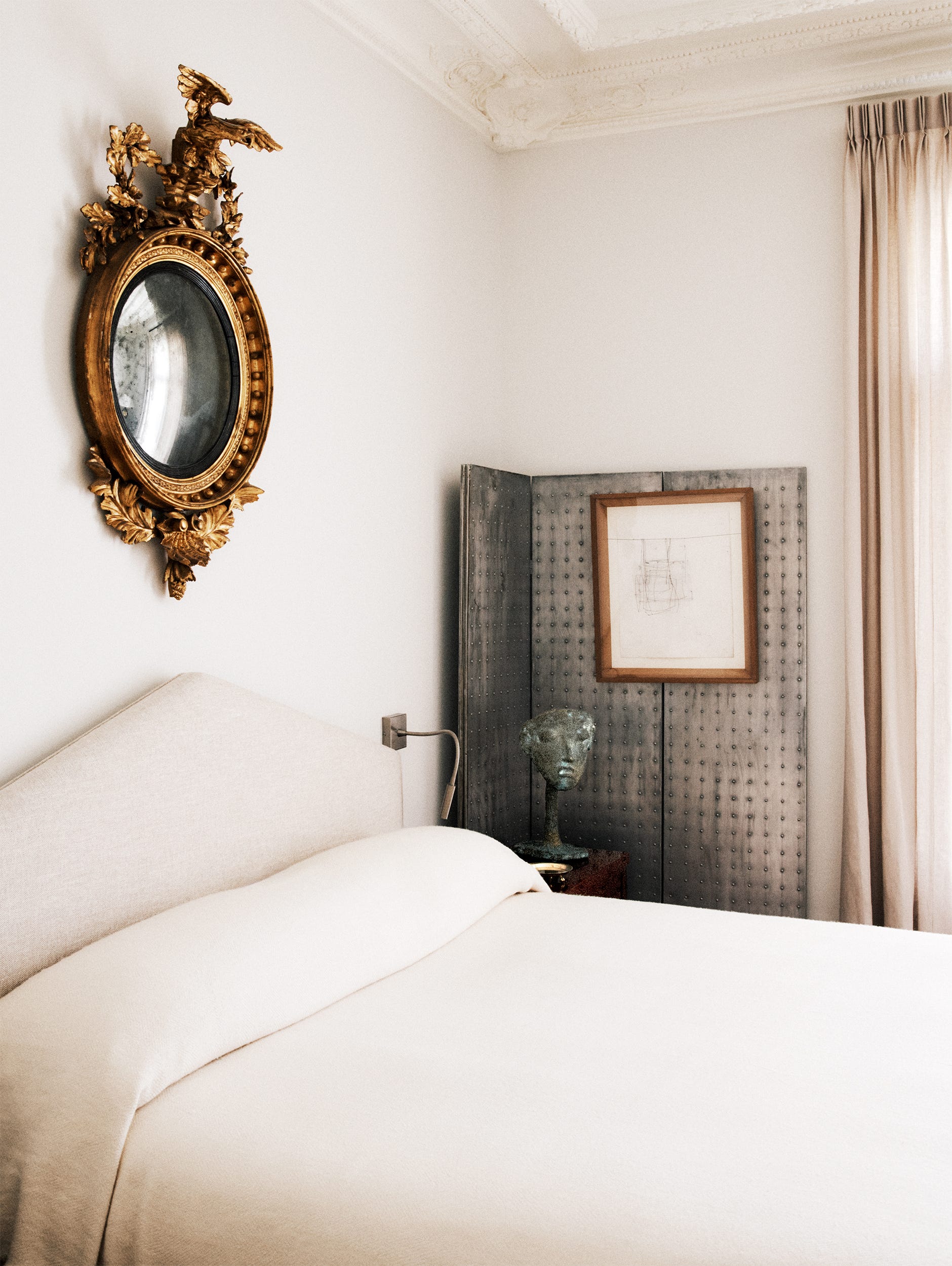 Elegant bedroom featuring a vintage mirror, a modern art piece, and a neutral color palette with soft textures.