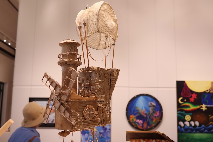 A brown sculpture of a structure suspended.
