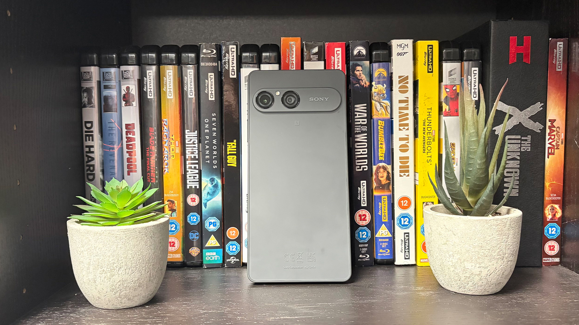 Sony Xperia 10 VIII smartphone leaned up against DVDs between cacti, rear of device