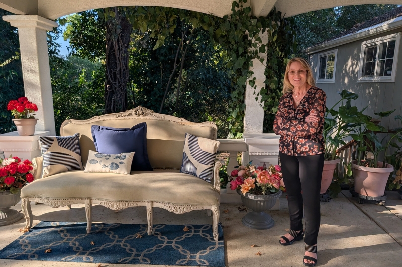 Award-winning photographer Diane Miller stands in her home studio beneath a covered balcony walkway. // SB Williams