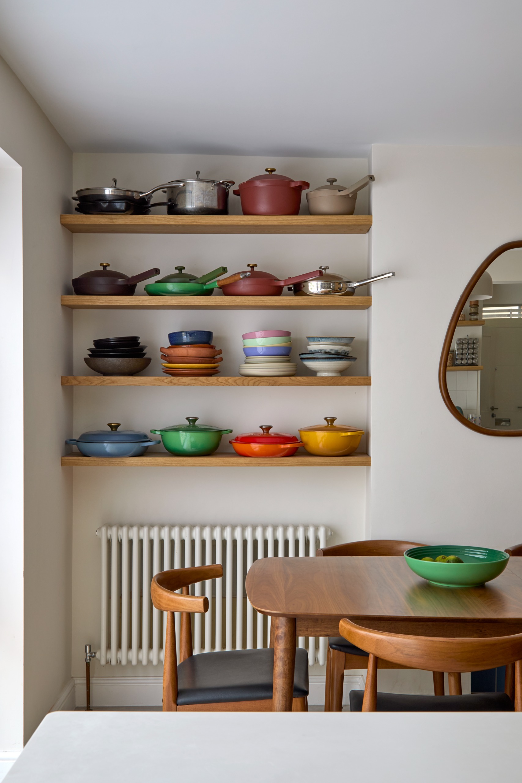 Open shelving with le creuset colorful pots above a dining table