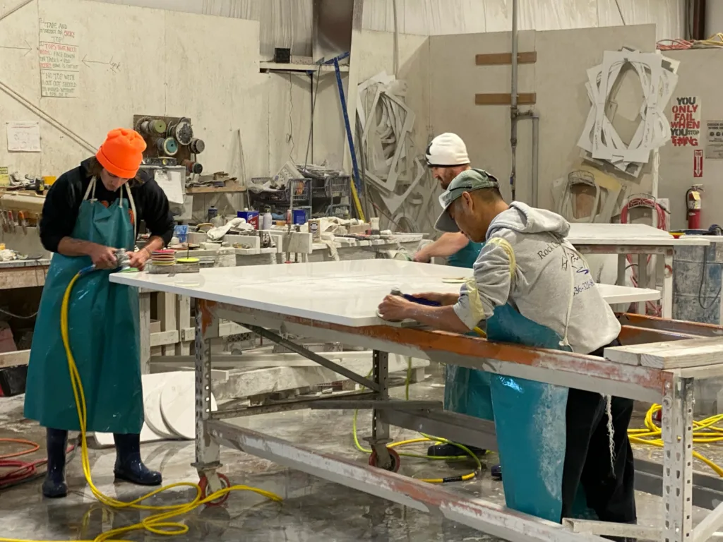 Three people polish a countertop