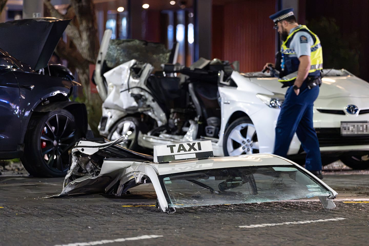Police investigate the scene in downtown Auckland where a taxi driver was trapped in his vehicle after it was hit by a Tesla driven by actor Cliff Curtis. Photo / Hayden Woodward