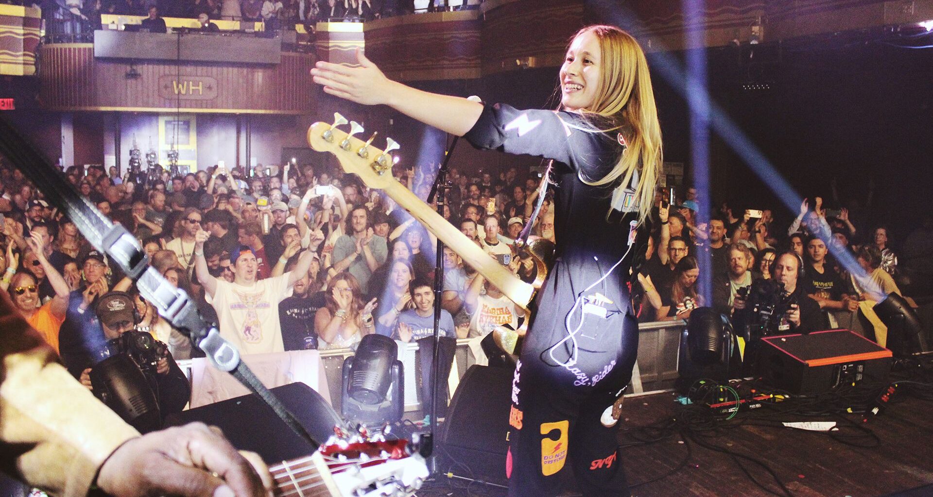 a rock band on stage in a crowded night club full of multicolored lights