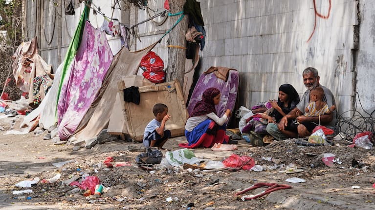 A displaced Yemeni family sits beside a makeshift shelter along a roadside in Aden, Yemen.
