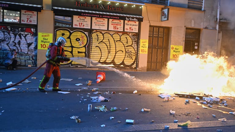 A firefighter extinguishes a fire during clashes with police a day after a demonstration against rising living costs, joining students' grievances, in Paris, Sunday, Oct. 18, 2026.