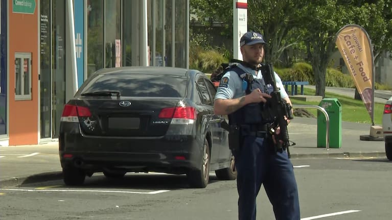 An armed police officer guards a vehicle with what appeared to be a bullet hole through the boot in Māngere, South Auckland.