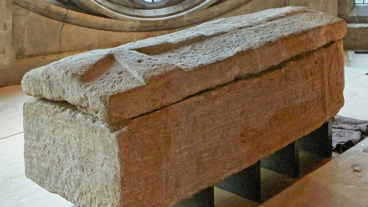 a limestone sarcophagus whose lid has been carved into a large cross
