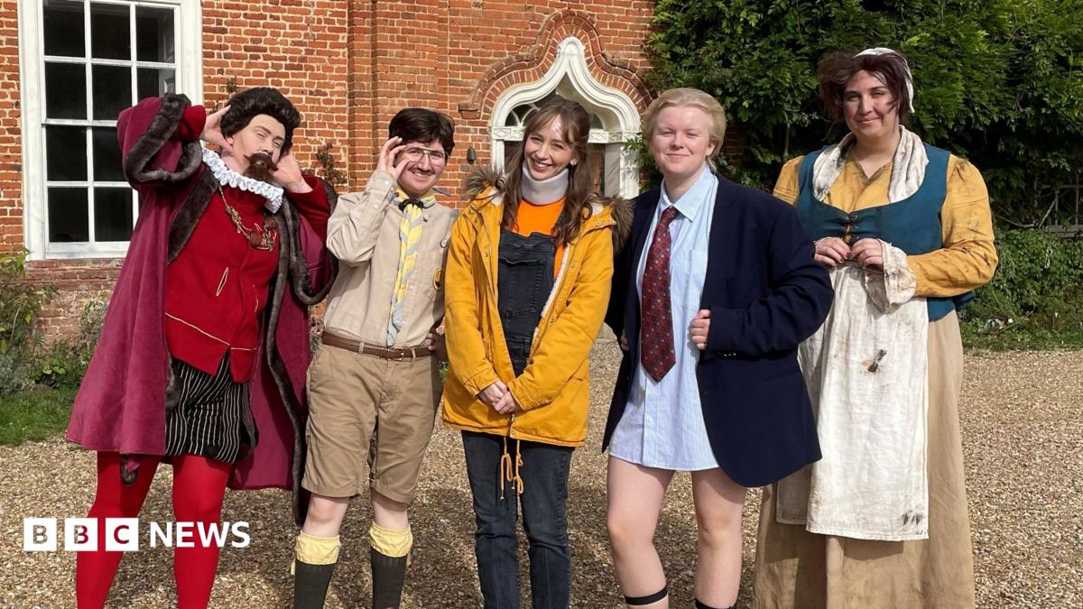 Five people dressed as characters from Ghosts. From left, they are in costumes as Sir Humphrey Bone, Pat, Alison Cooper, Julian Fawcett MP and Mary from the series. They are pictured outside the brick manor house with a gravel driveway that forms the set of the programme.