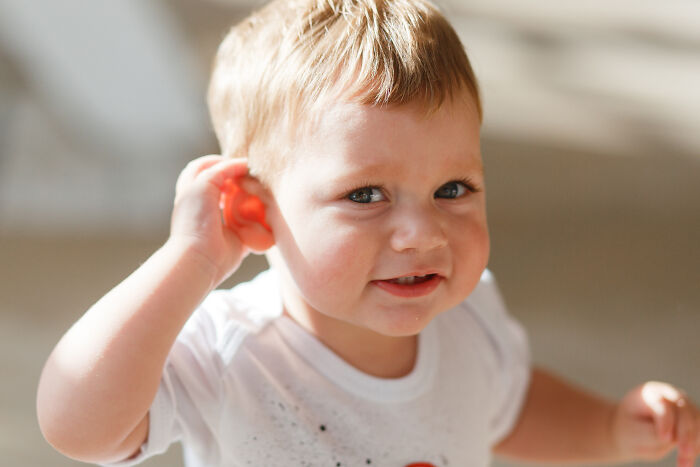 A toddler touching his ear while feeling sick with an ear infection