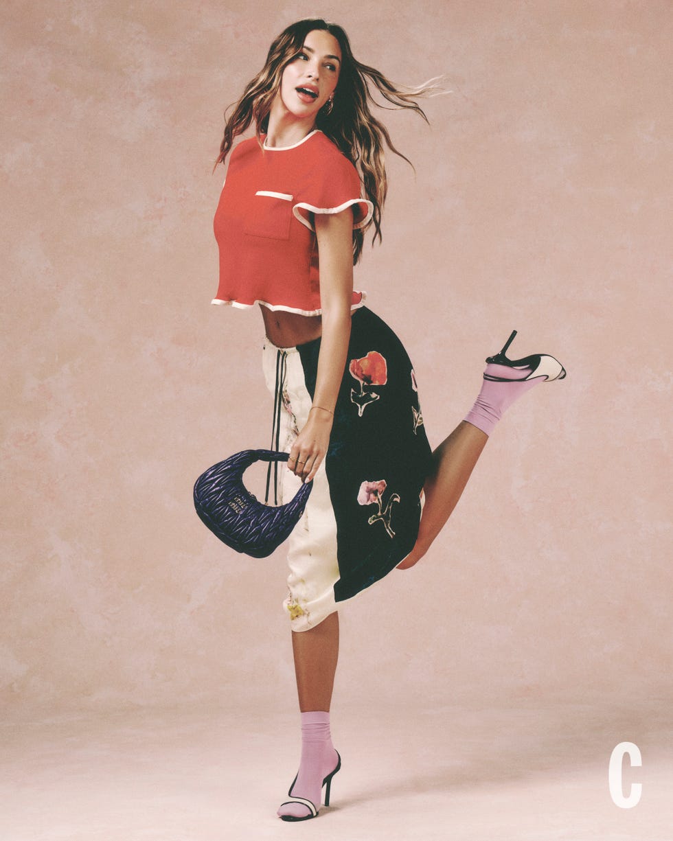 model posing playfully in colorful fashion with floral skirt and purple handbag model posing playfully in colorful fashion with floral skirt and purple handbag