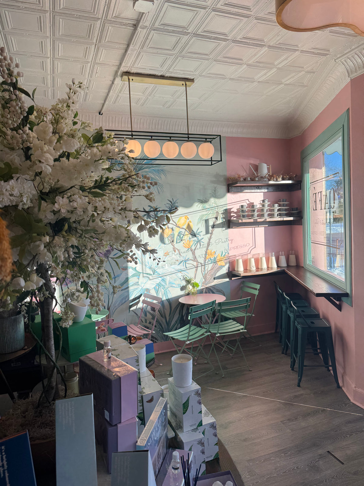 Inside a BloomBar Café et Fleurs shop with pink walls, a floral mural and mint green bistro chairs