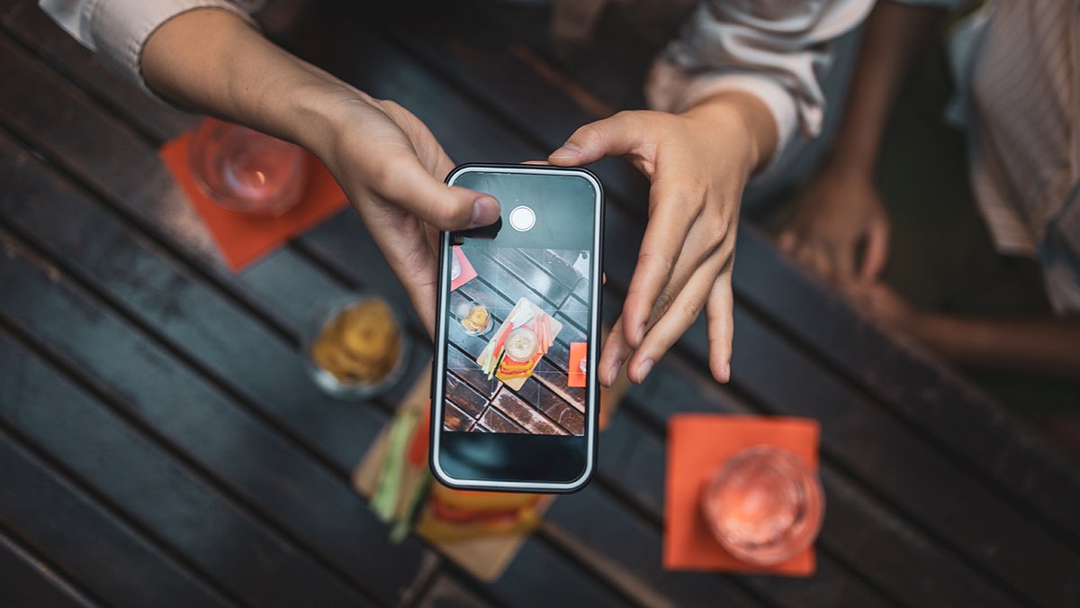 A person takes a picture on an iPhone.