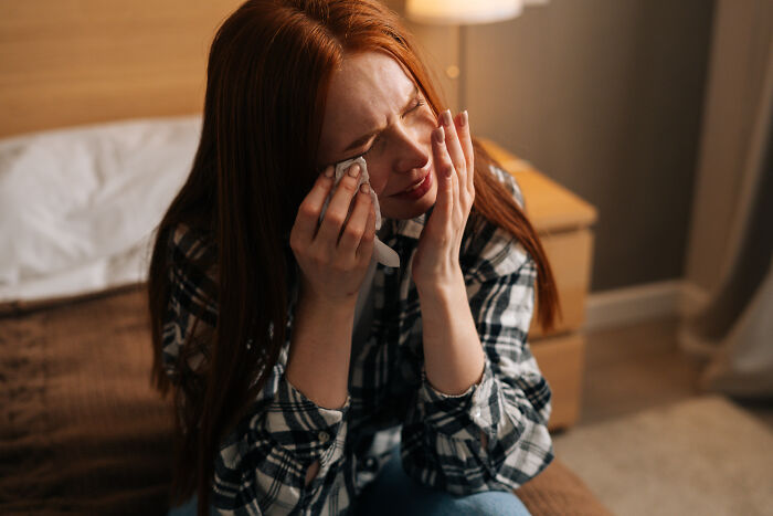 Upset woman crying on her bed after feeling sick and overwhelmed by a negative medical consultation