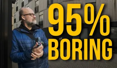 Bald bearded man in glasses and a blue puffer jacket holding a camera near a modern building, with large yellow text reading 95% BORING.