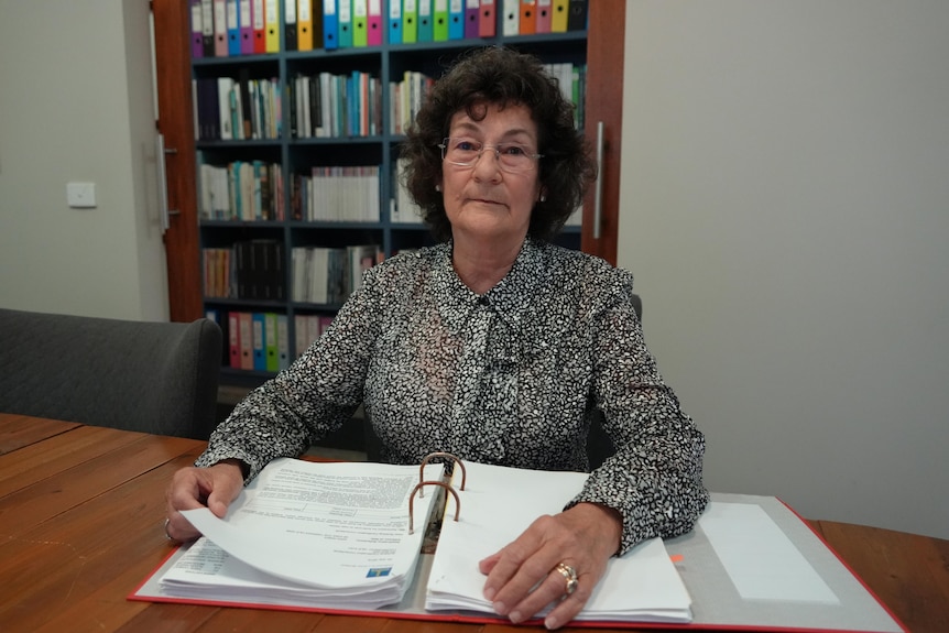 Woman looks at camera while sitting at desk with documents in front of her