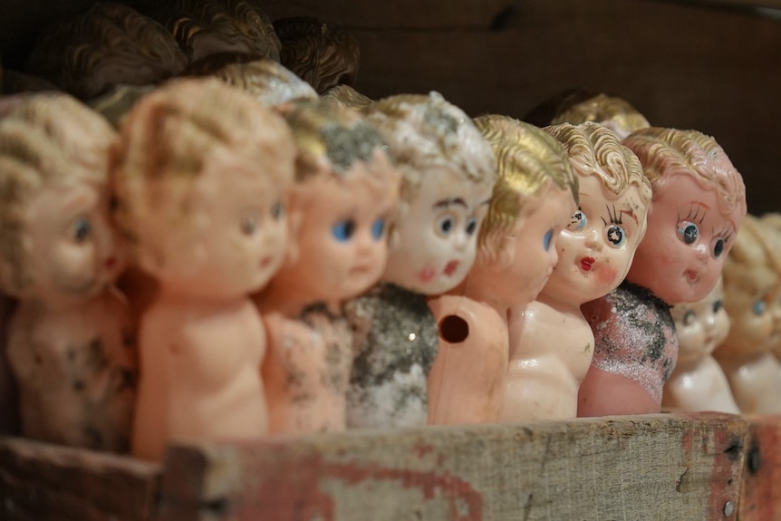 Wooden box of dolls up close that look old and used.