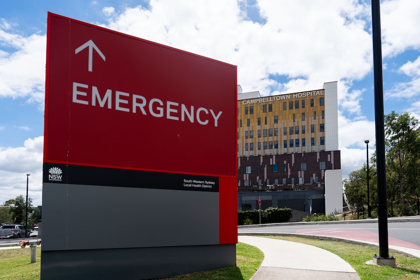 Campbelltown Hospital yellow multi-storey building on a sunny day, with a red emergency sign.