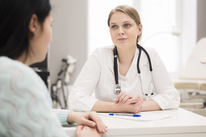 A female doctor listening attentively to a patient in a medical office while discussing being sick.