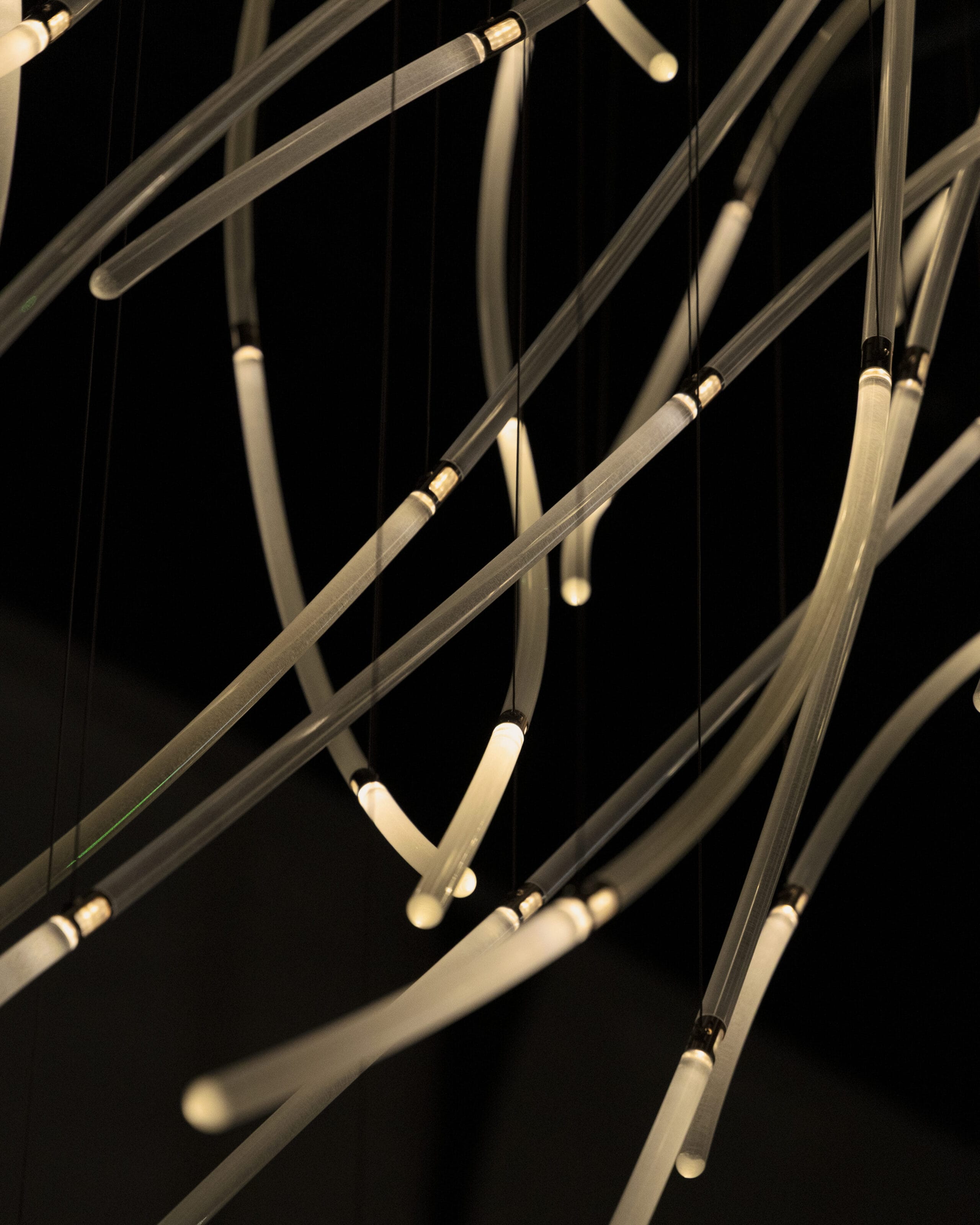 a detail of a suspended LED light sculpture with luminescence moving through undulating tubes