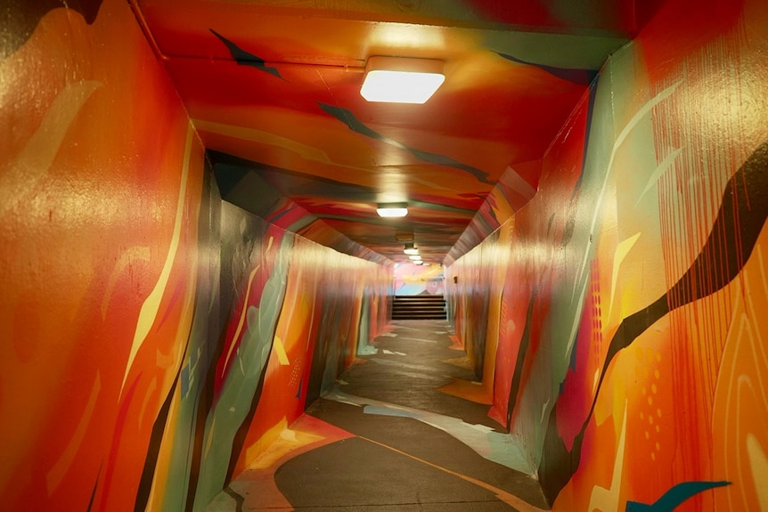 A tunnel painted with colourful street art.