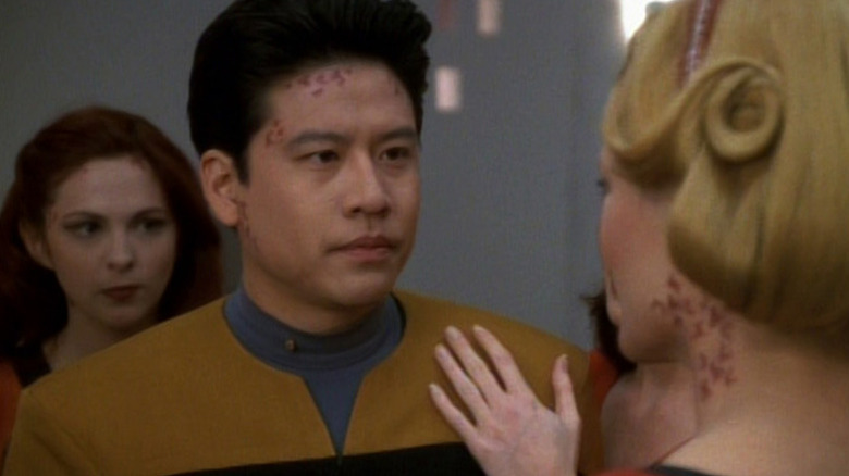 Harry Kim (Garrett Wang) with alien marks on his face is approached by two alien women in Star Trek: Voyager