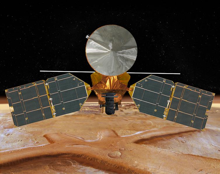 A spacecraft that looks like a cylinder, with a cone head and two solar panels coming off its side, floating through space with Mars in the background.