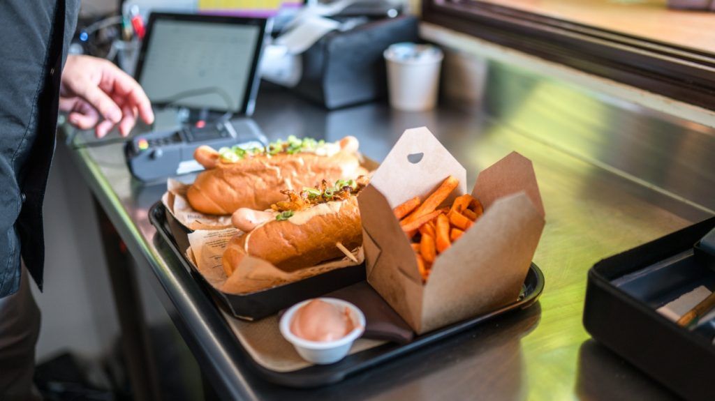 two subs and a pack of fries on a tray
