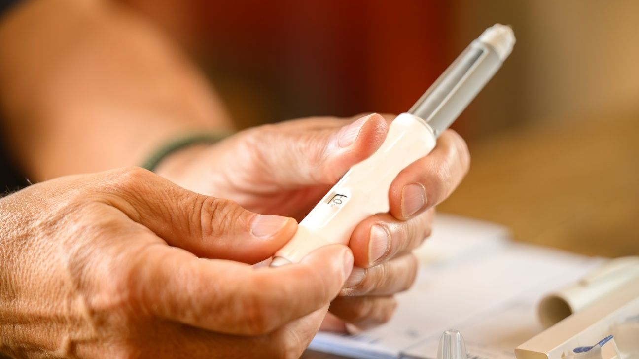 Male holding a GLP-1 injection pen