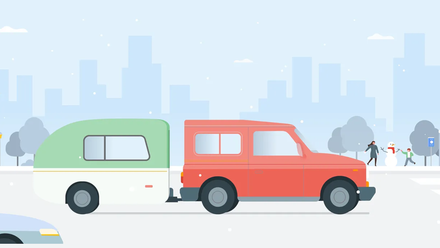 A red truck drives with a trailer hitch past a family building a snowman