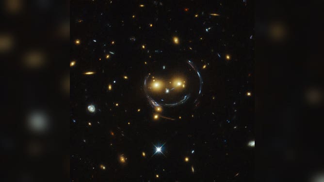 Galaxy cluster forms a smiley face in the dark corners of the universe.
