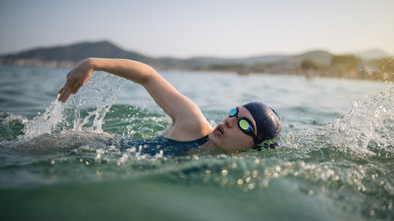 A person in full swimming gear swimming outdoors