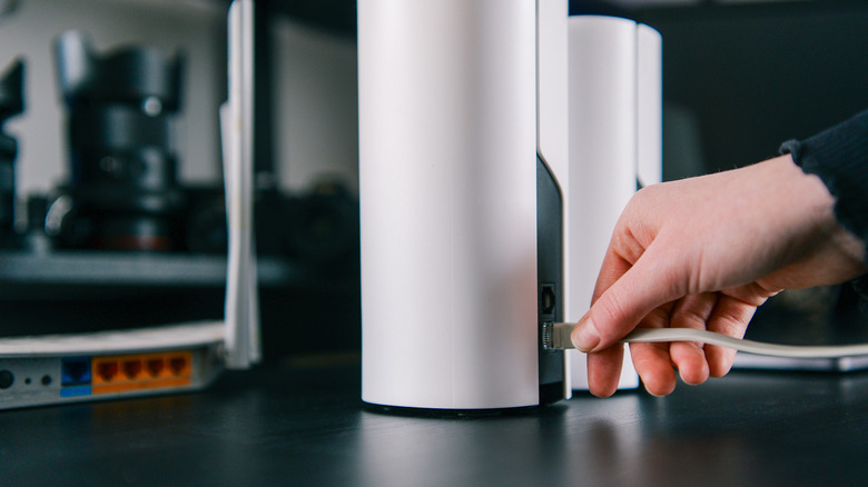 A person inserts an Ethernet port into a Wi-Fi mesh system