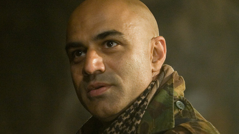 Raza Hamidmi al-Wazar of the Ten Rings holds up a piece of molten metal with a set of tongs in a cave in Marvel Studios' Iron Man.