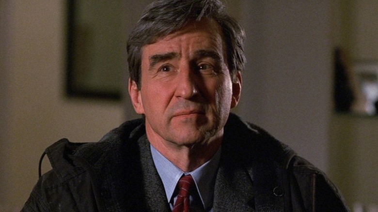 Sam Waterston as Jack McCoy, sitting in a chair in Law & Order.