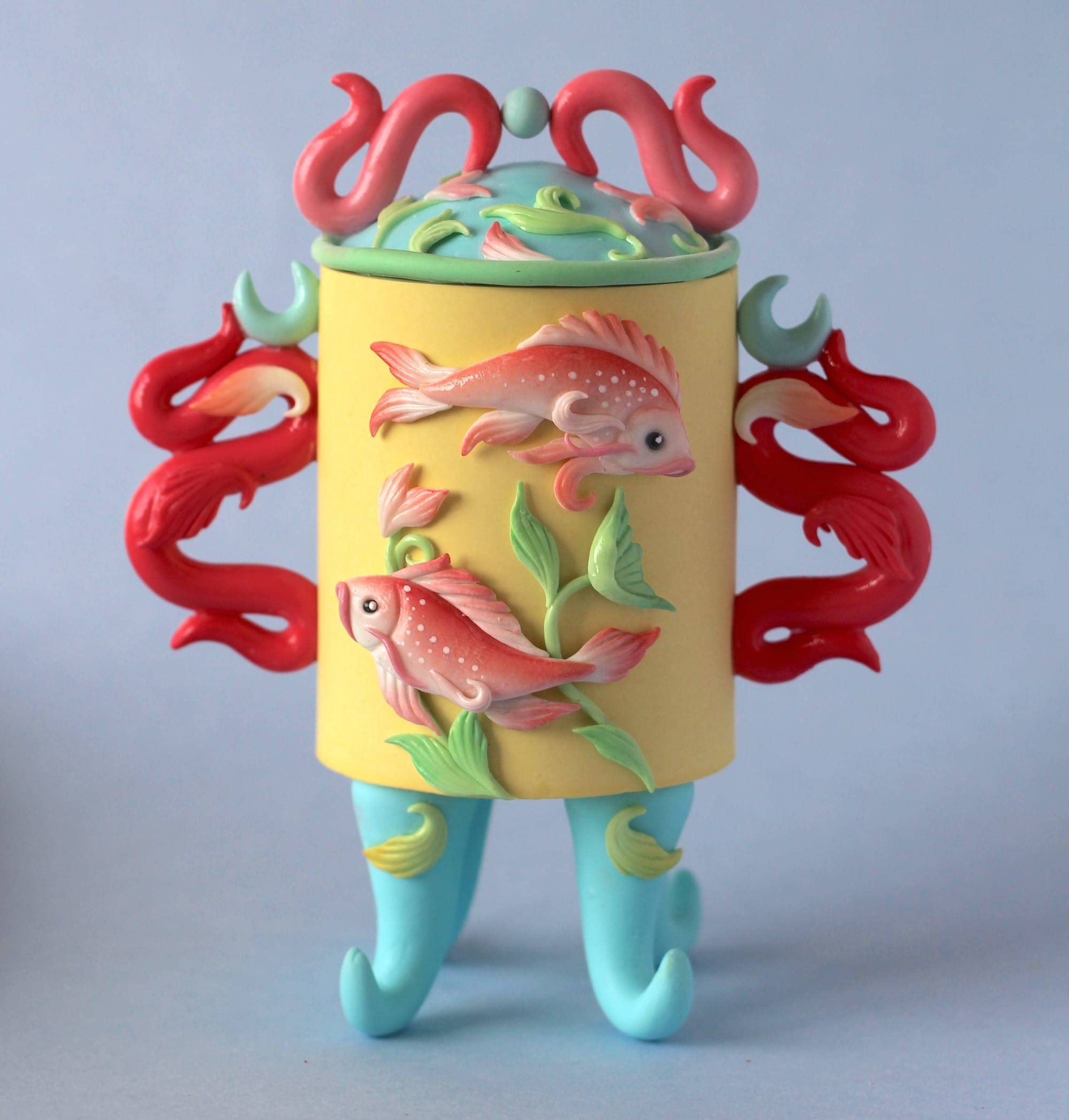 a stylized snuff bottle sculpture made from polymer clay featuring a relief of two fish