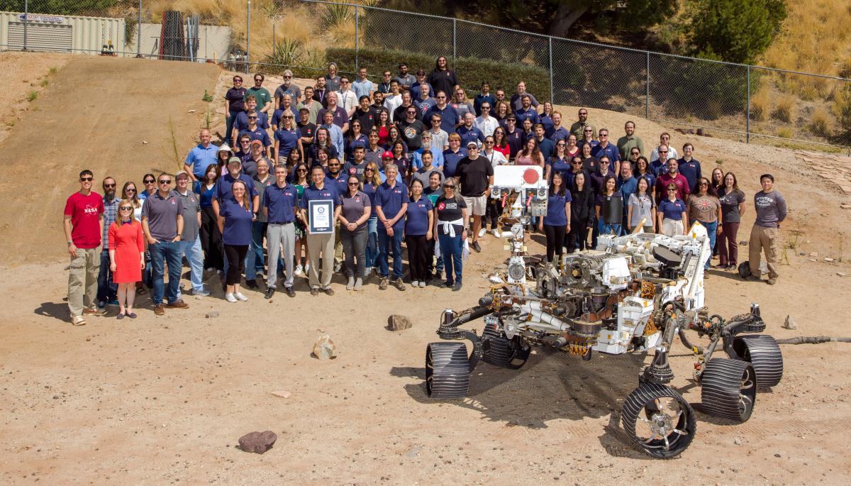 NASA engineers pose with a replica Mars rover in the Mars Yard at JPL.