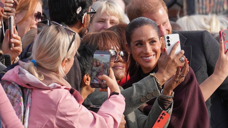 Meghan stops to take pictures with fans in Nottingham.