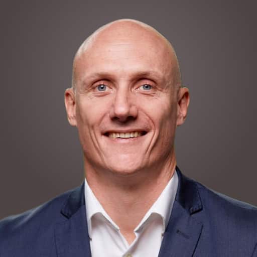 A headshot of a smiling middle-aged bald man.