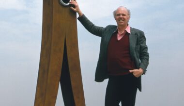 a historical photograph of artist Claes Oldenburg standing beside a giant, 10-foot clothespin sculpture