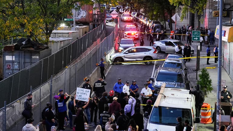 People gather at the scene of a shooting as law enforcement work the area.