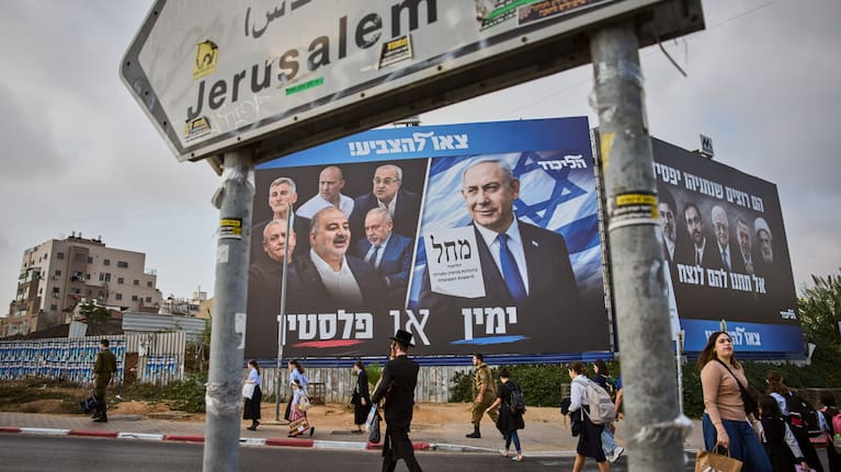 People walk past a Likud party campaign billboard featuring Israeli Prime Minister Benjamin Netanyahu.
