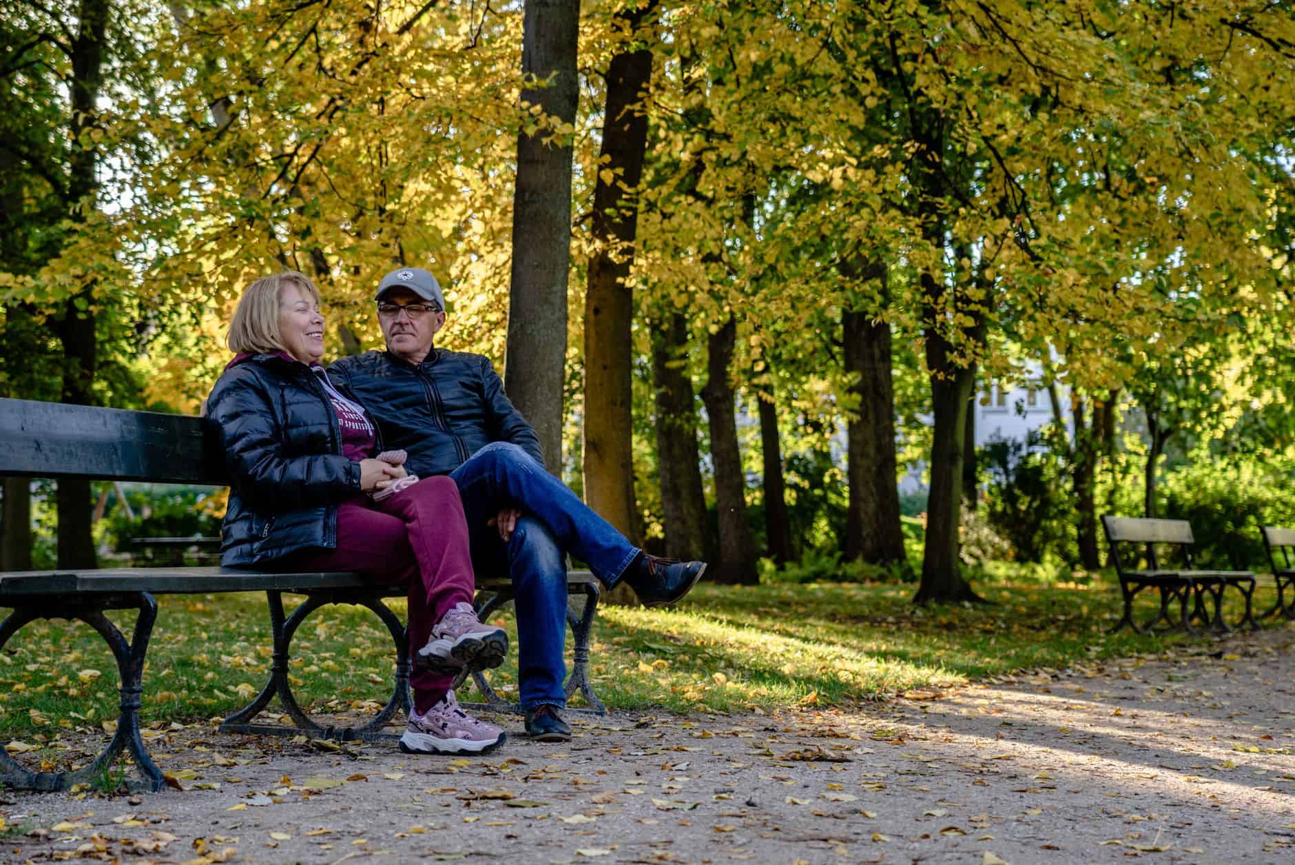 an elderly couple sitting on the bench at the park