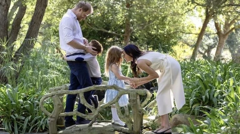 Prince Archie can be seen hugging his father Prince Harry while Meghan holds hands with Princess Lilibet. (Source: Supplied)